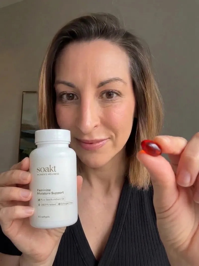 A woman holding a bottle of Soakt and one softgel